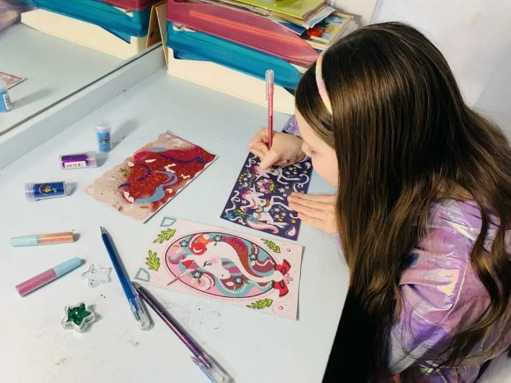 Carolina decorates unicorn drawings with the biodegradable glitter set brought back from Paris.