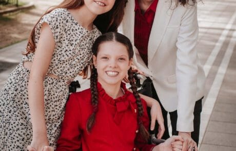 Portrait of two sisters on a tree-lined walk; the elder one is in a wheelchair.