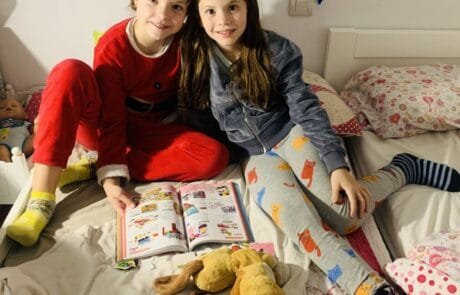 Isabel and her friend Martina, the book’s illustrator, leaf through a catalogue sitting on the bed.