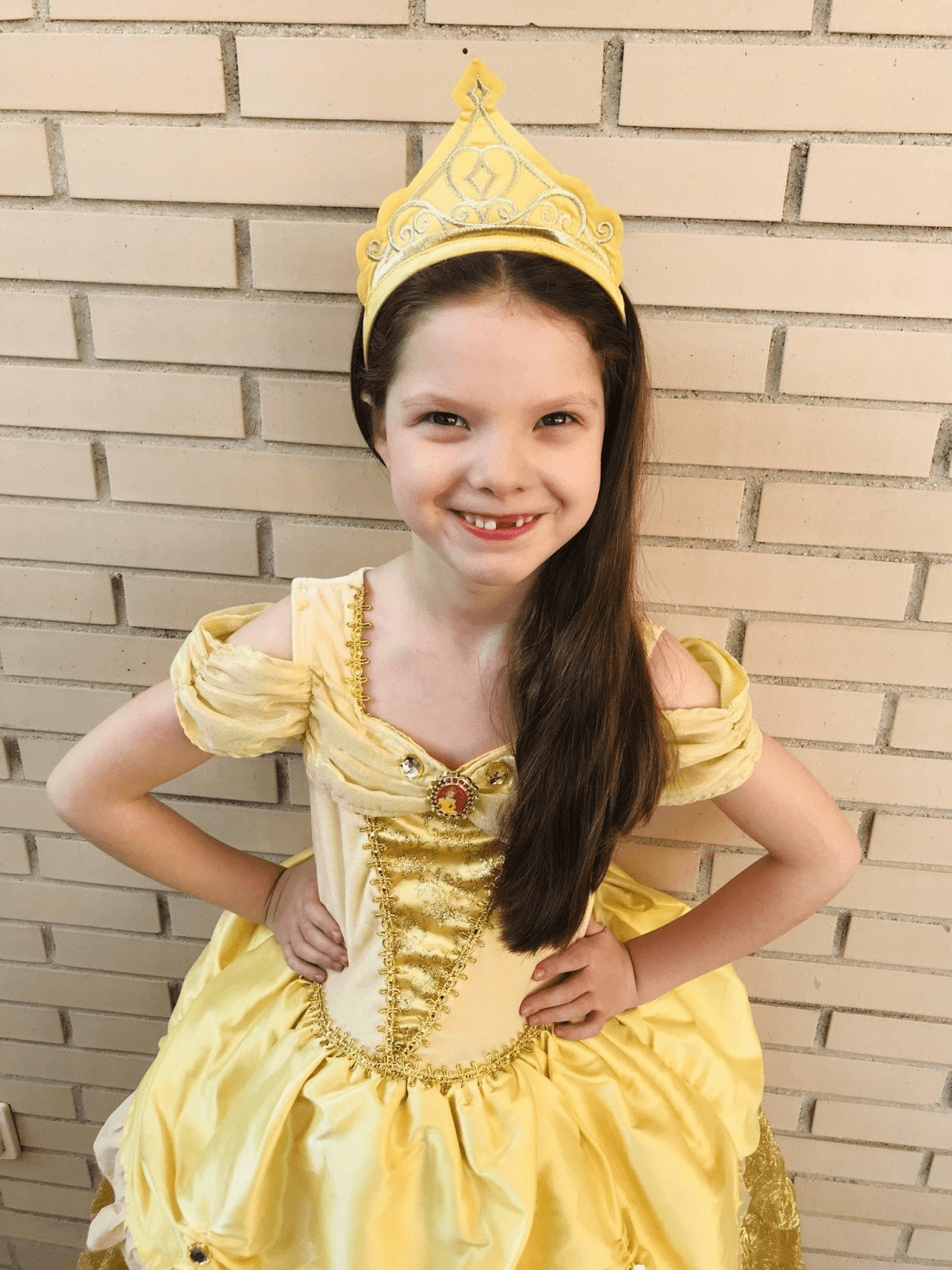 Carolina Purpurina dressed as Princess Belle in a yellow gown and crown, aged six.