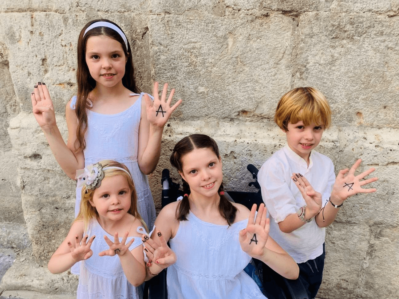Carolina and her siblings pose with the Tubb4a Foundation letters painted on their hands for the 2024 calendar.
