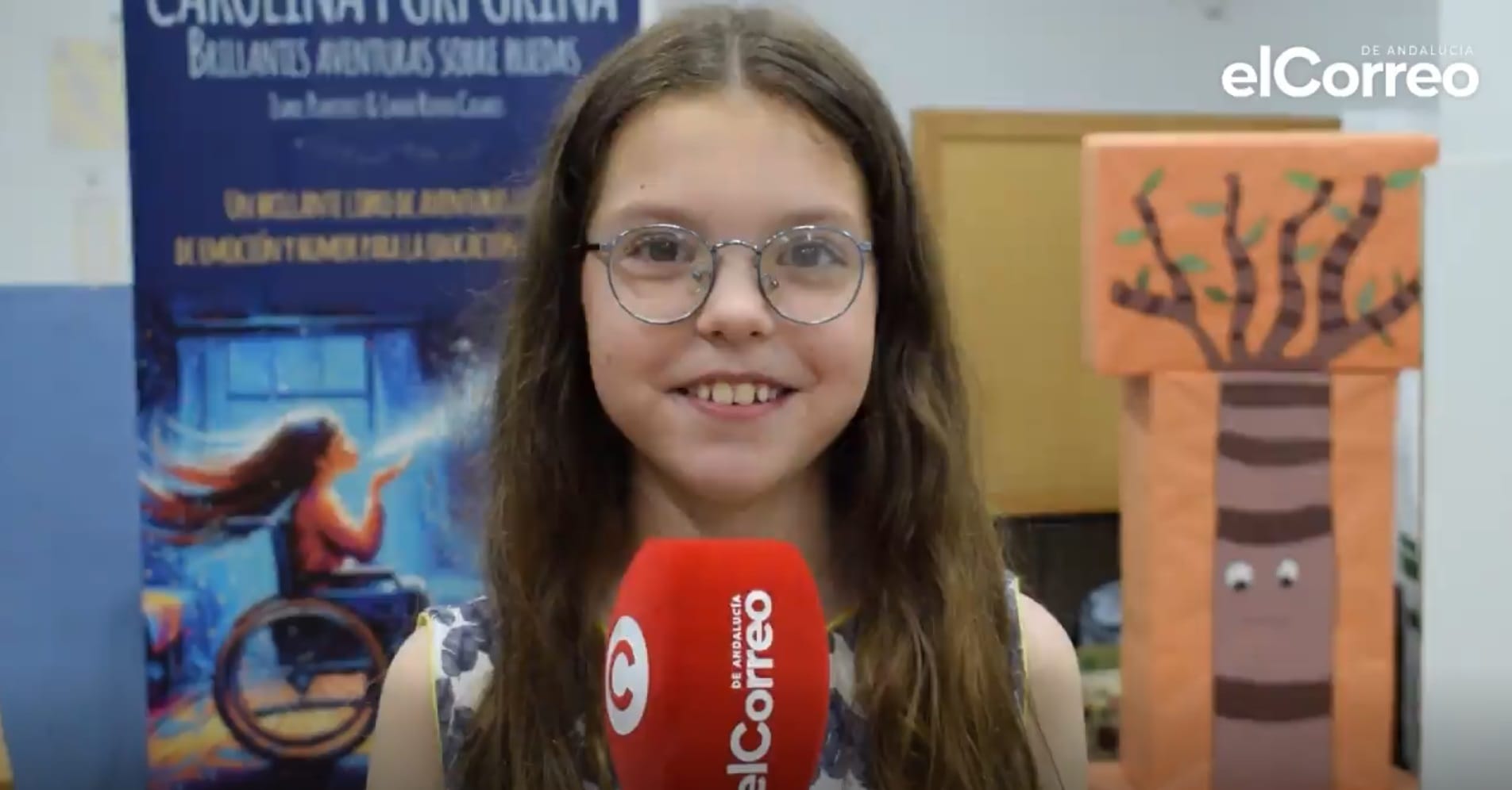 Isabel, in her round glasses, answers into an elCorreo de Andalucía microphone beside the book’s banner.