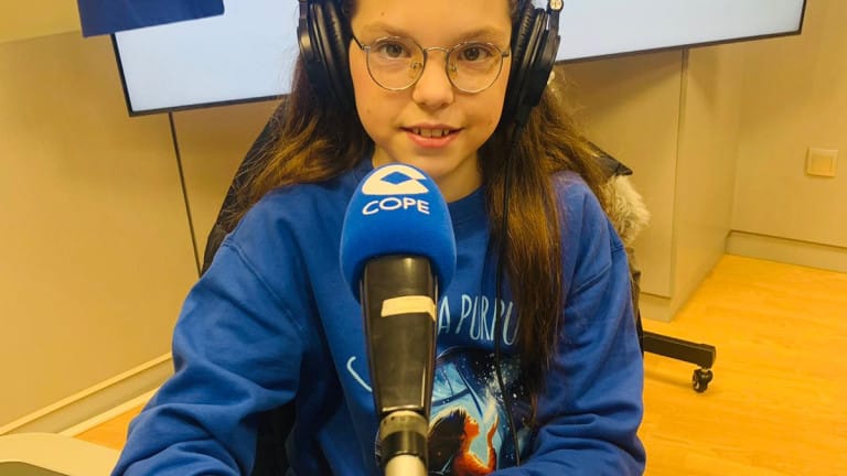 Isabel, in headphones and a “Carolina Purpurina” sweatshirt, speaks into the COPE microphone in the studio.