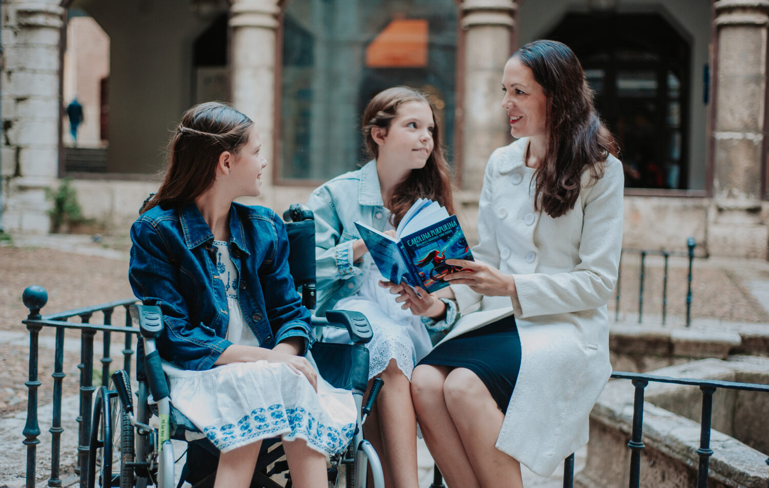 Laura reads the book to Carolina, in her wheelchair, and Isabel in an old courtyard.