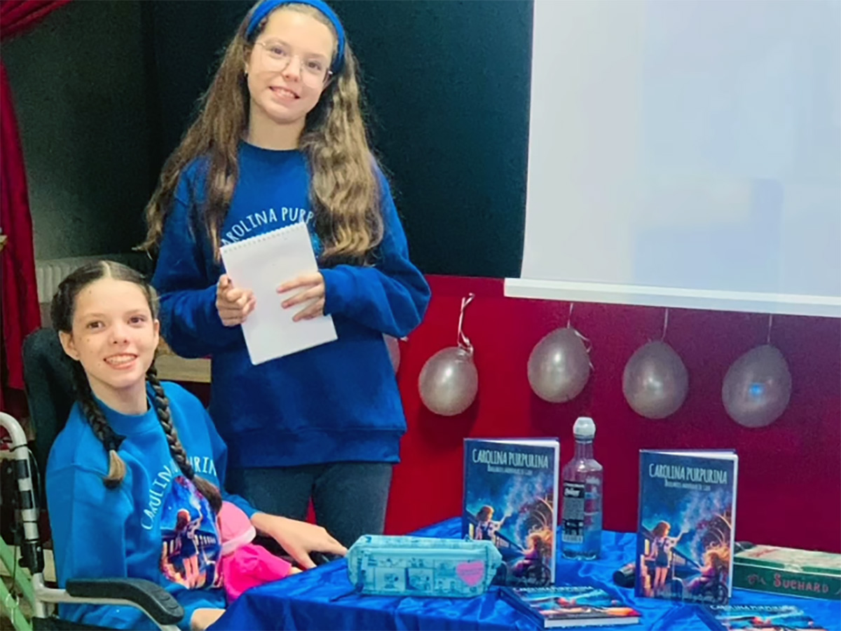 Isabel and Carolina beside the book table during the visit to CEIP Marqués de Valero, in Béjar.