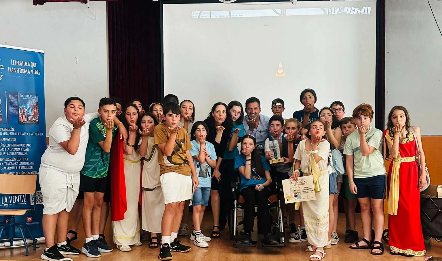 Pupils and teachers blow glitter around Carolina, who holds the certificate beside the trophy.