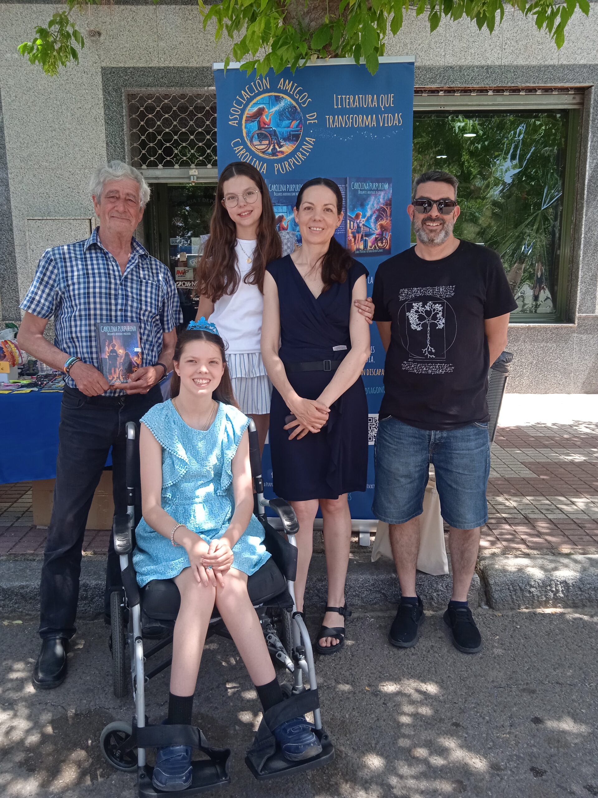 Book launch: the family in front of the Asociación Amigos de Carolina Purpurina banner.