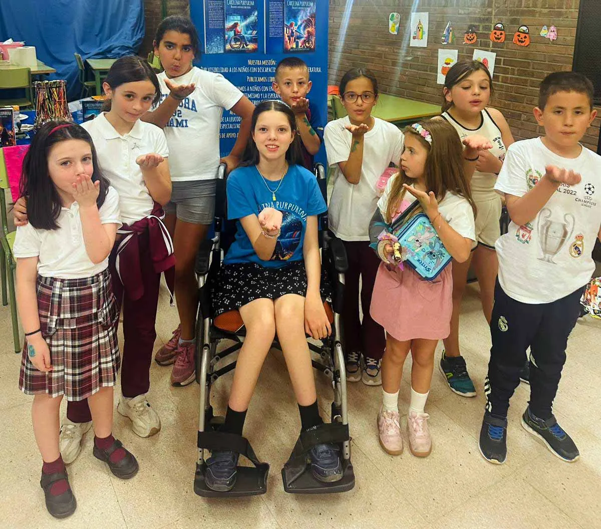 Carolina, in her wheelchair, surrounded by pupils blowing glitter from their palms.