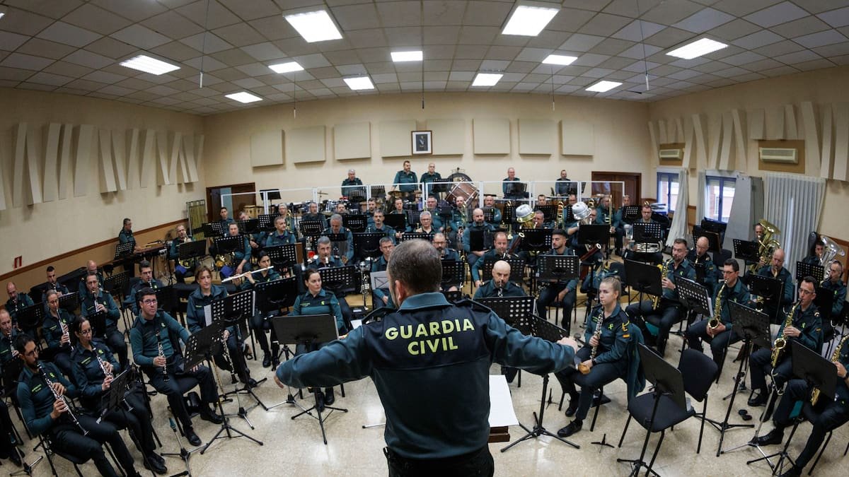 A conductor in a Guardia Civil jacket, seen from behind, leads a rehearsal of the band that gave a concert to benefit the association.