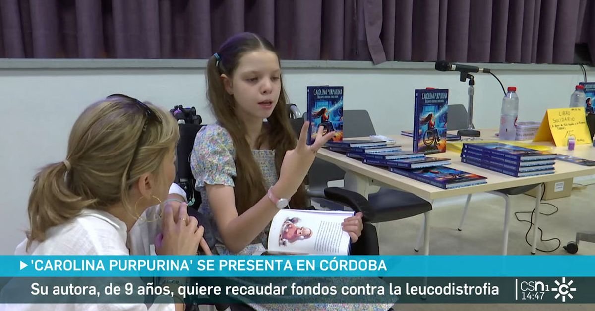 Canal Sur report in Córdoba: a seated girl holding the open book talks with a woman; behind them, the table stacked with copies of the book.